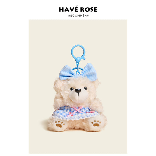 Stuffed teddy bear with a blue bow and dress on a beige background, featuring the brand 'Have Rose'.