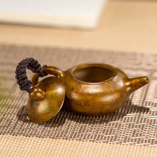 Bronze teapot on a textured surface with a blurred background