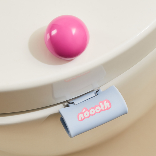 Pink ball on a toilet seat with a blue clip labeled 'néooth' Label Toilet Lifter
