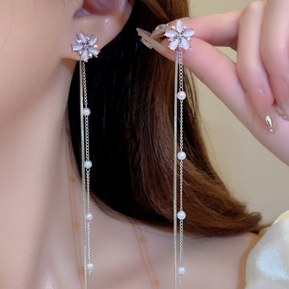 A woman wears a floral earring with a long chain and pearl details. It's really beautiful and elegant.