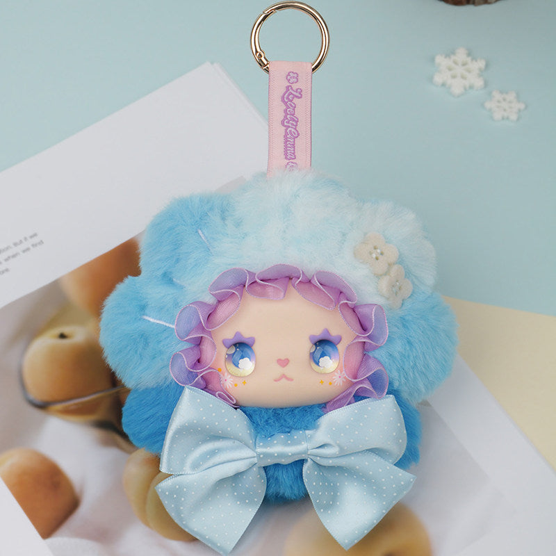 Plush keychain with cartoon character wearing a blue outfit and hat on a light blue background. Lovely Emma