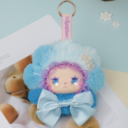 Plush keychain with cartoon character wearing a blue outfit and hat on a light blue background. Lovely Emma