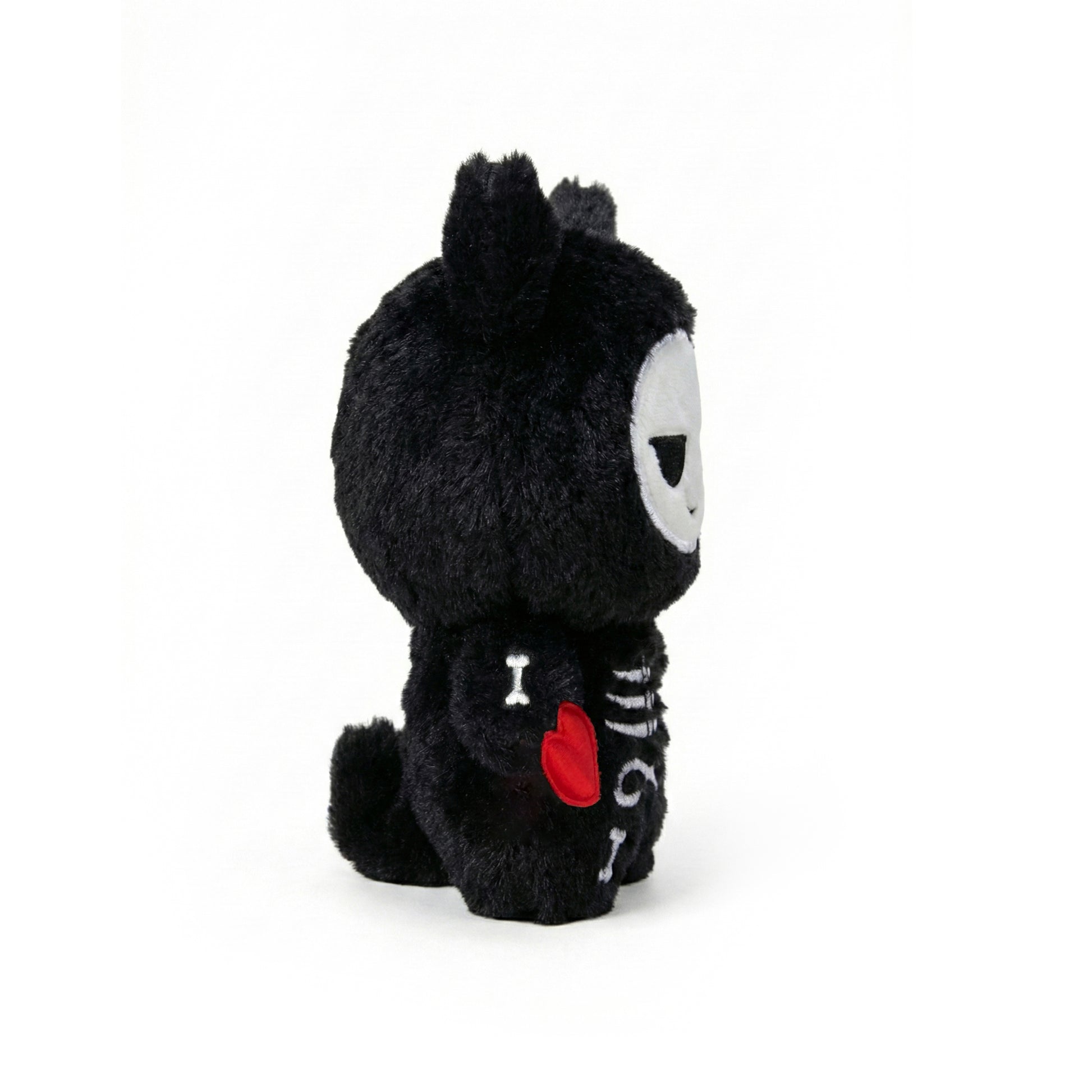 Black plush toy with a red heart and white face on a white background  called Koko the skeleton 