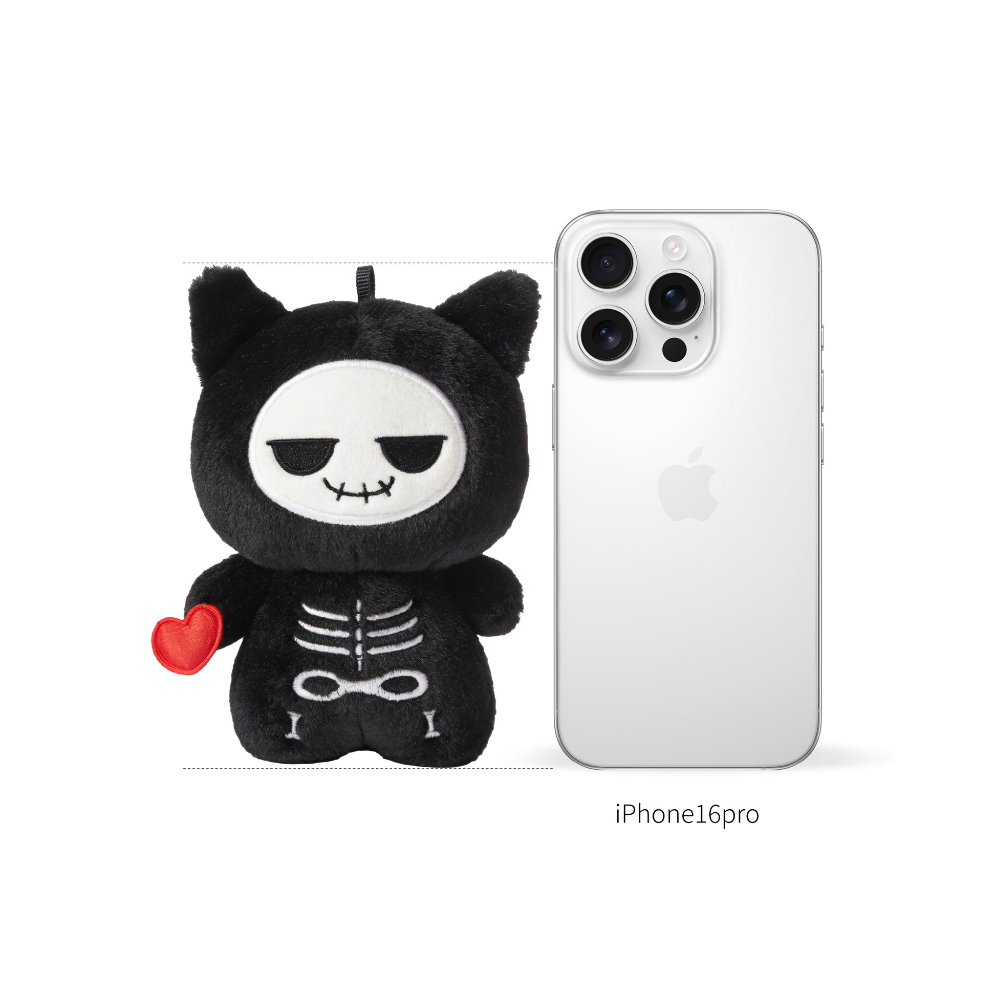 Black skeleton plush toy called Koko the skeleton with a red heart next to an iPhone 16 Pro on a white background