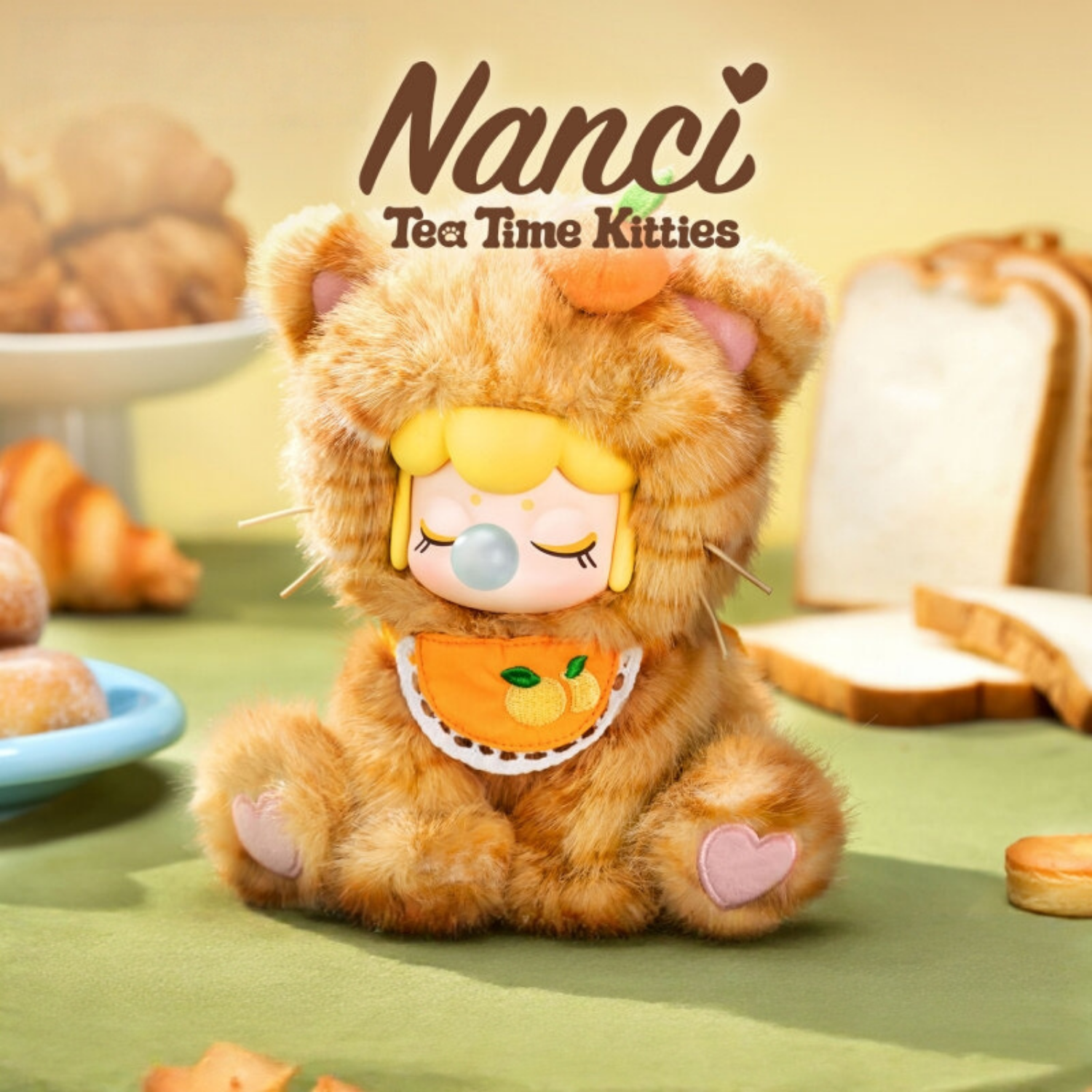 This Nanci's Tea Time Pulsh Kitty toy is in orange. It looks soft and plump, with an orange decoration on its head and a orange-patterned bib around his neck. It's very cute.