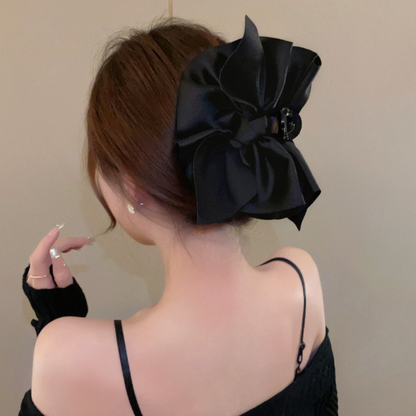 A woman wears a large black hair bow. It's really elegant.